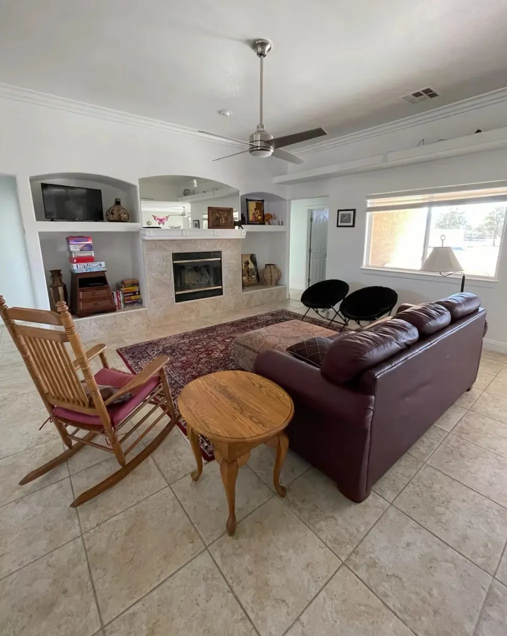 The living room, with a fireplace in arched built-ins, a leather sofa and a rocking chair