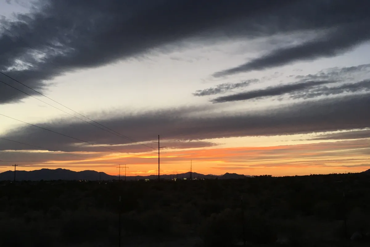 An orange sunset glowing under long clouds over the mountains in Pahrump