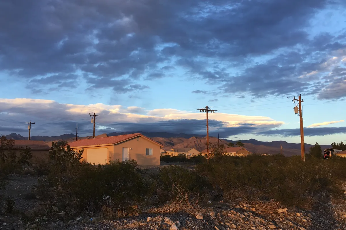 A quiet Pahrump street at sunset with the mountains behind the houses