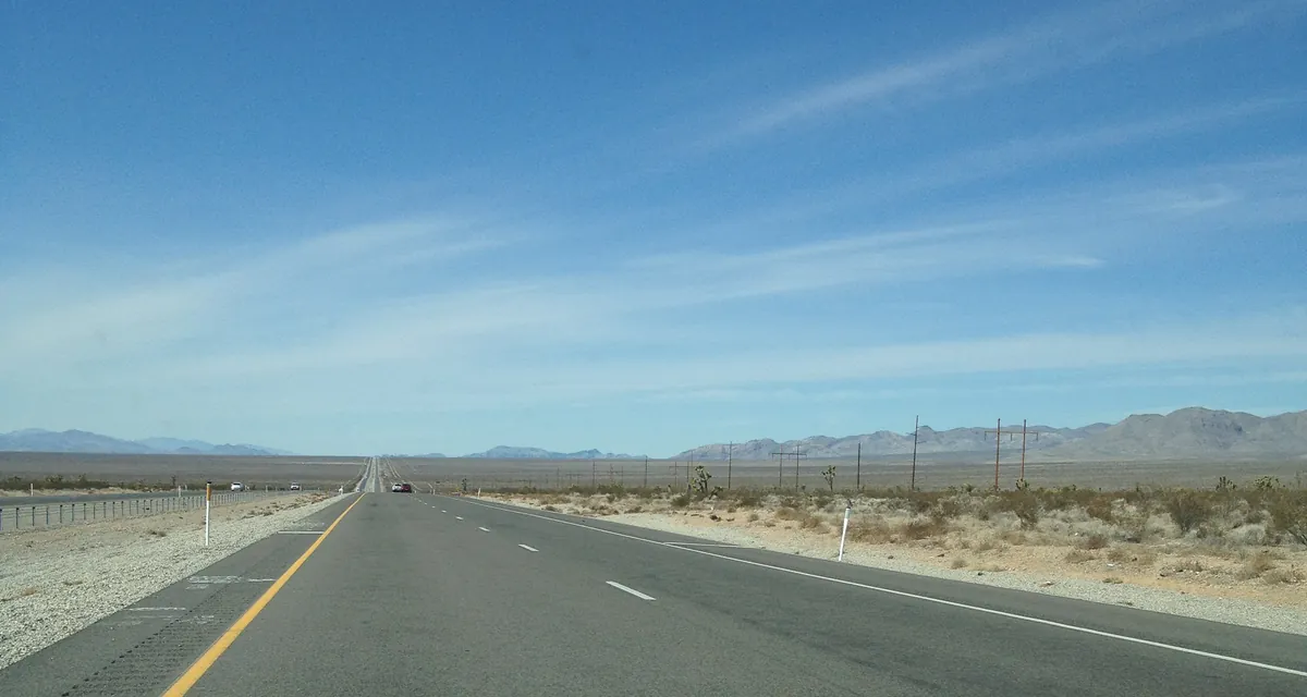 The open road through the Pahrump Valley under a wide blue sky
